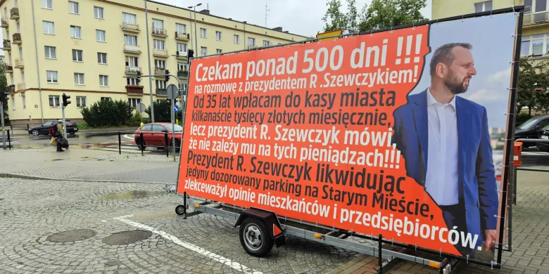 Spór o parking przy ul. Nowowiejskiego nabiera rozgłosu. Przedsiębiorca wyjechał na ulice z wymownym banerem