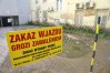 Przy budynku zawisły żółte tabliczki ostrzegające przed niebezpieczeństwem